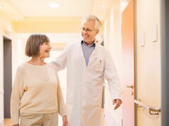 En äldre kaukasisk läkare som samtalar med sin äldre kaukasiska kvinnliga patient